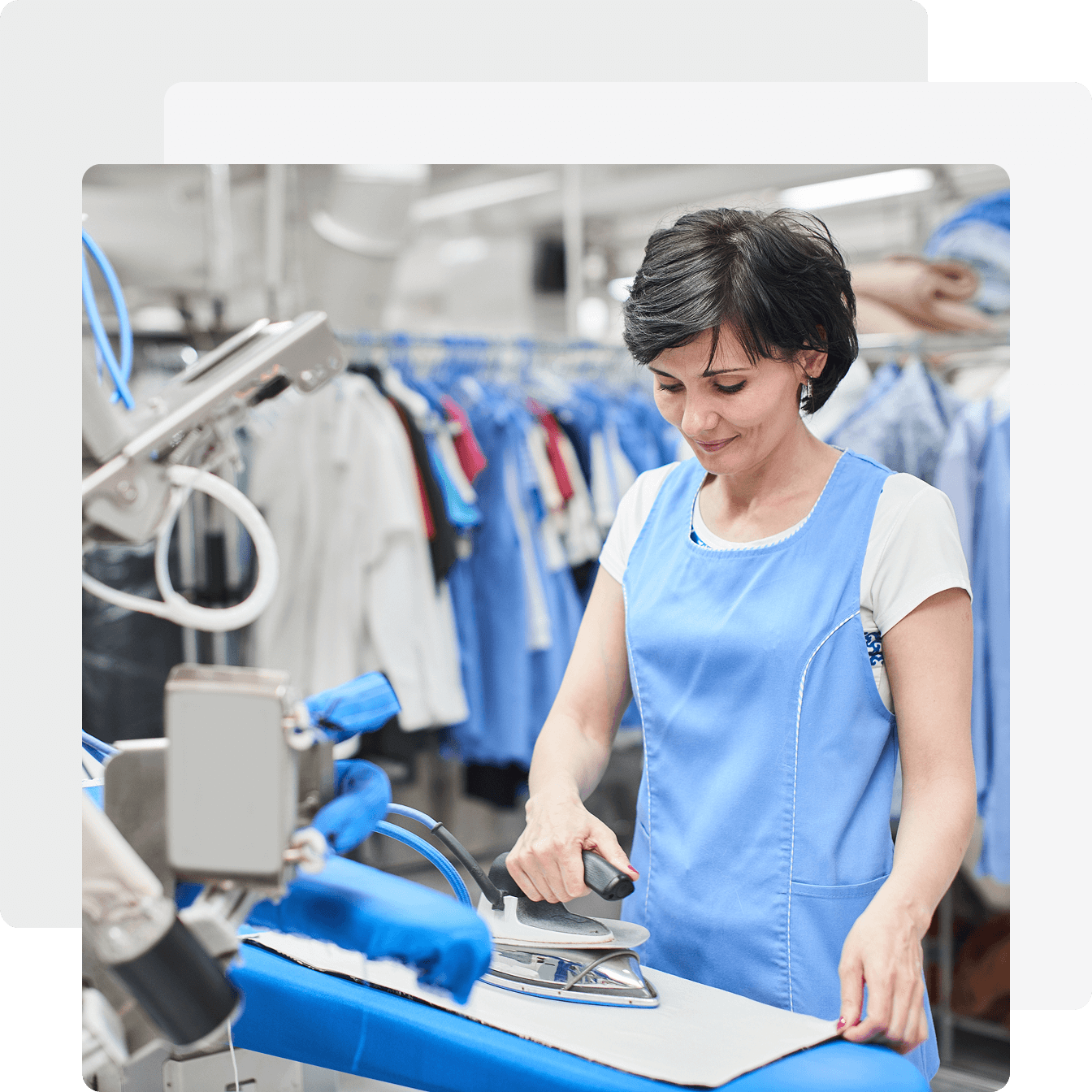 Woman ironing clothes in a laundry facility.